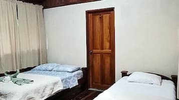 Quarto com duas camas, piso de madeira, teto de madeira, uma porta e uma luminária no teto.