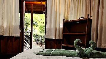 Una habitación con una cama, una estantería de madera y vistas a través de una puerta abierta.