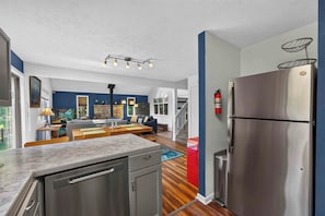 A modern kitchen with a stainless steel refrigerator, wooden cabinets, and a marble countertop. - Cozy 2BD 2BA Hideaway w/ Pond Views & Firepit (East Stroudsburg)
