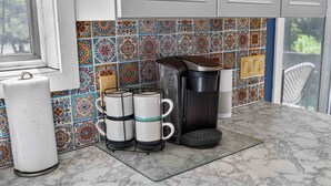 Une cuisine dotée d’un plan de travail en marbre, d’une machine à café, d’une bouilloire et d’un porte-essuie-tout.