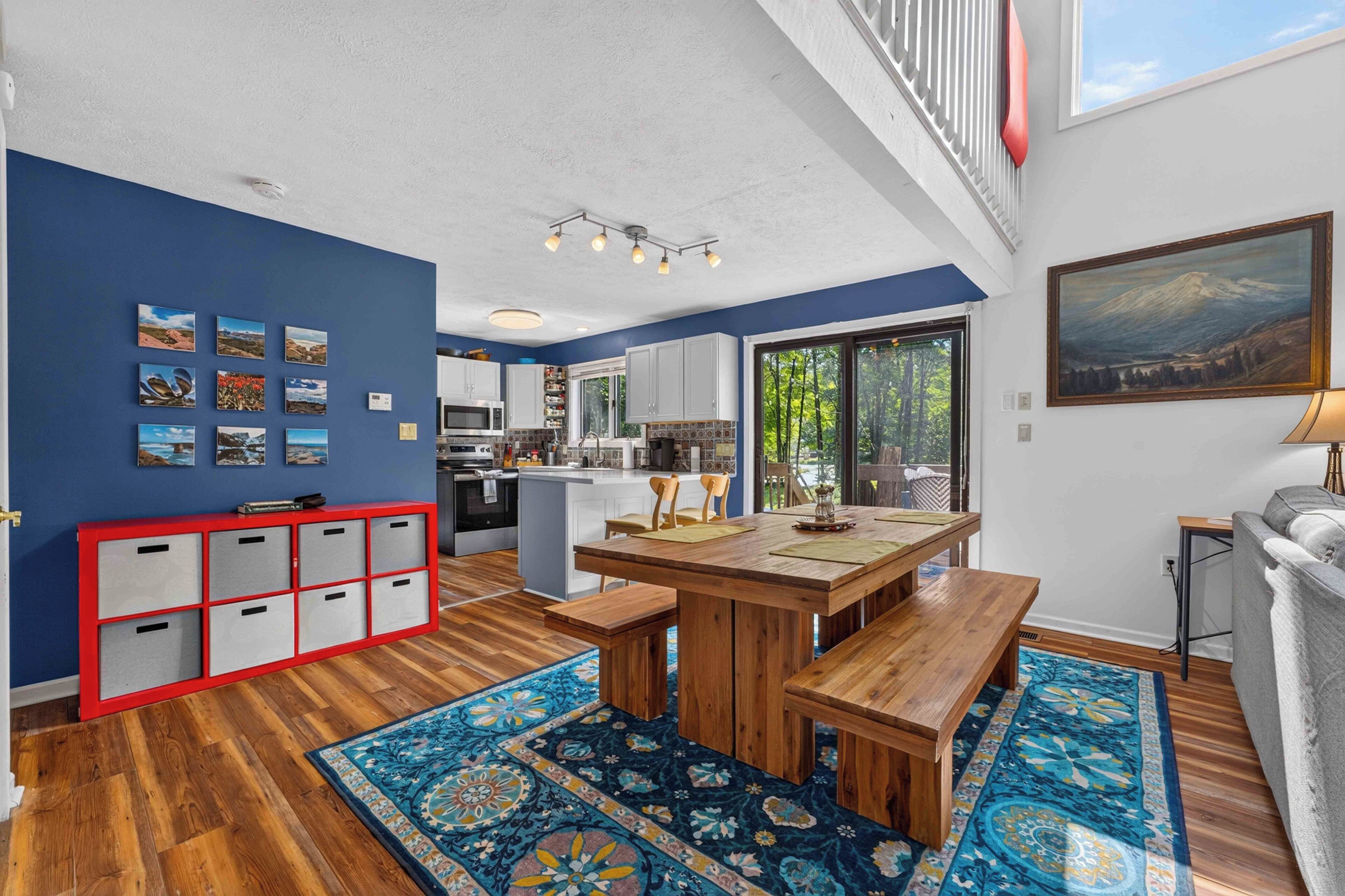 A modern kitchen with white cabinets, a wooden dining table, and a red storage unit.
