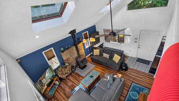 A spacious living area with a high ceiling, a fireplace, a sofa, and a dining table.