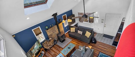 A spacious living area with a high ceiling, a fireplace, a sofa, and a dining table.