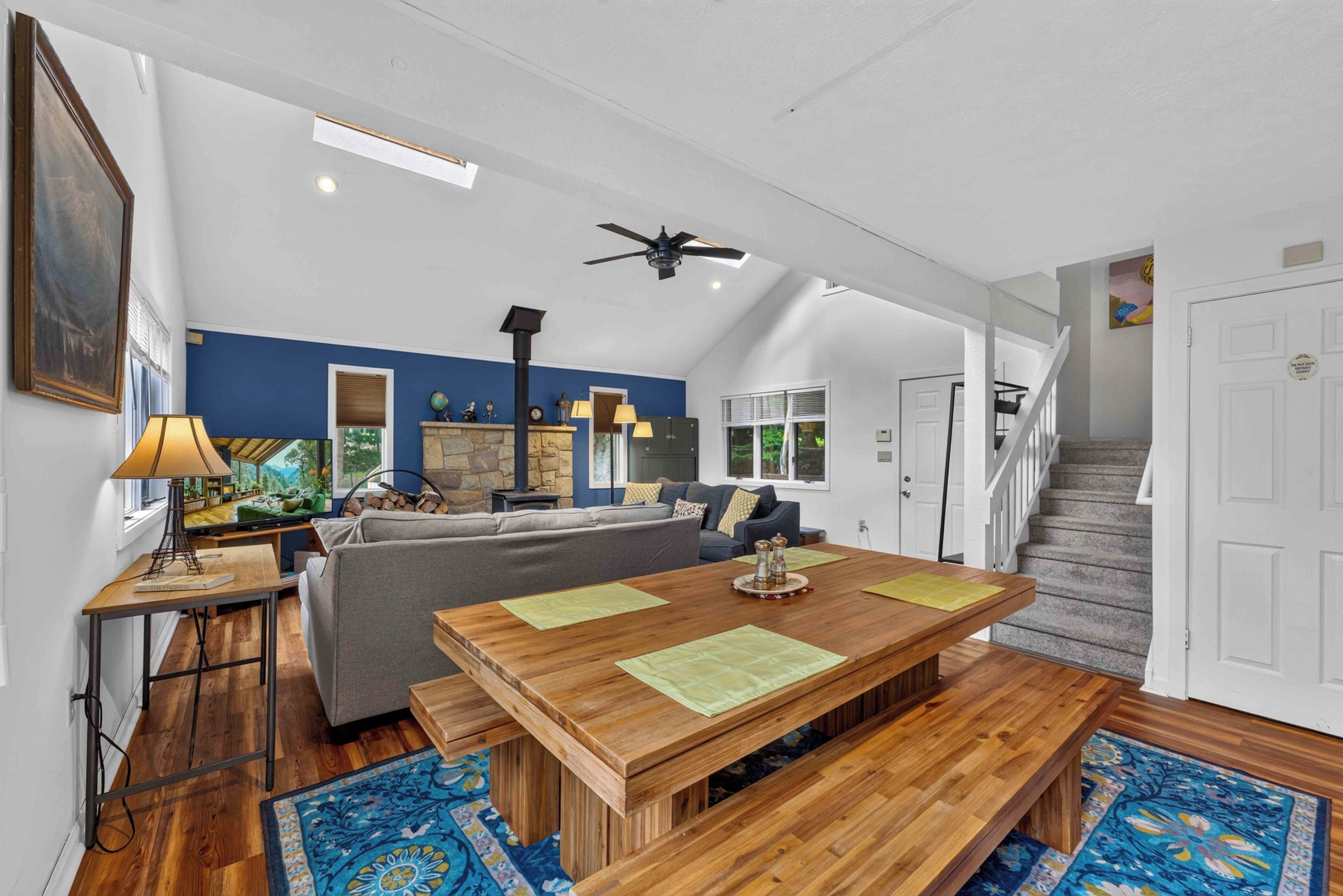 A spacious living area with a wooden dining table, a sofa, and a fireplace.