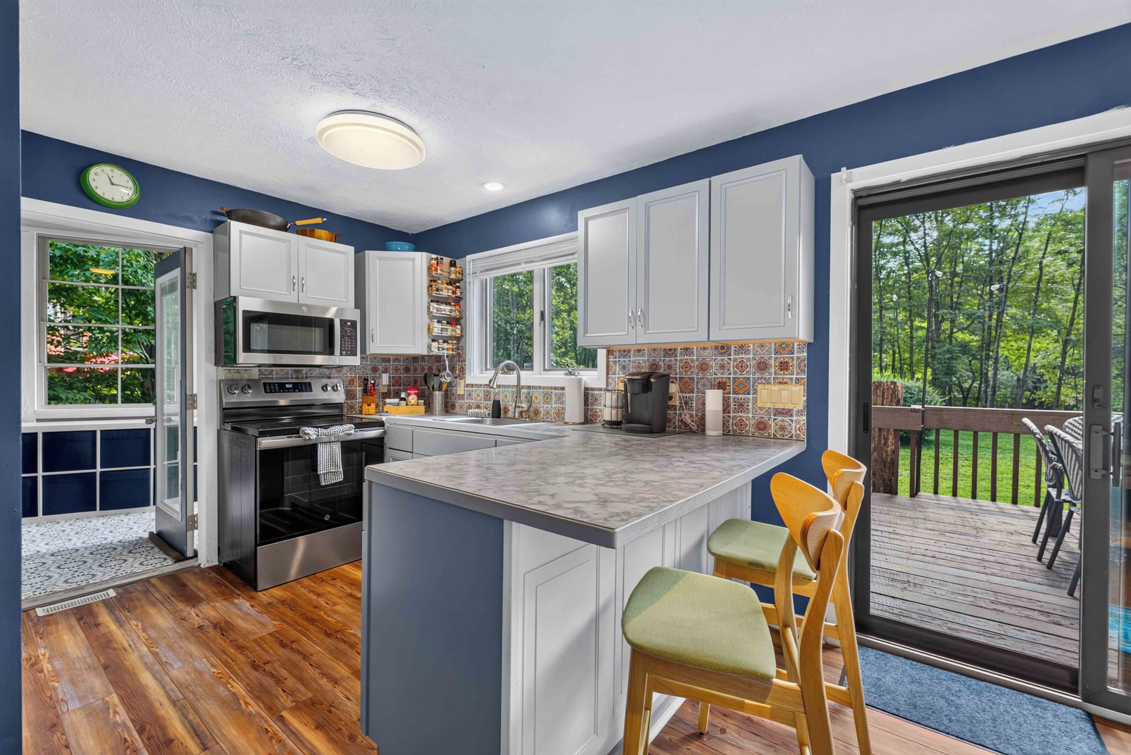 A modern kitchen with a large island, built-in appliances, and a view to a deck.