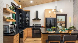 A modern kitchen with wooden cabinets, a central island, and a dining area with chairs. - Shady Ridge - Hot Tub~Game Room~Star Gazing Dome (Mineral Bluff)