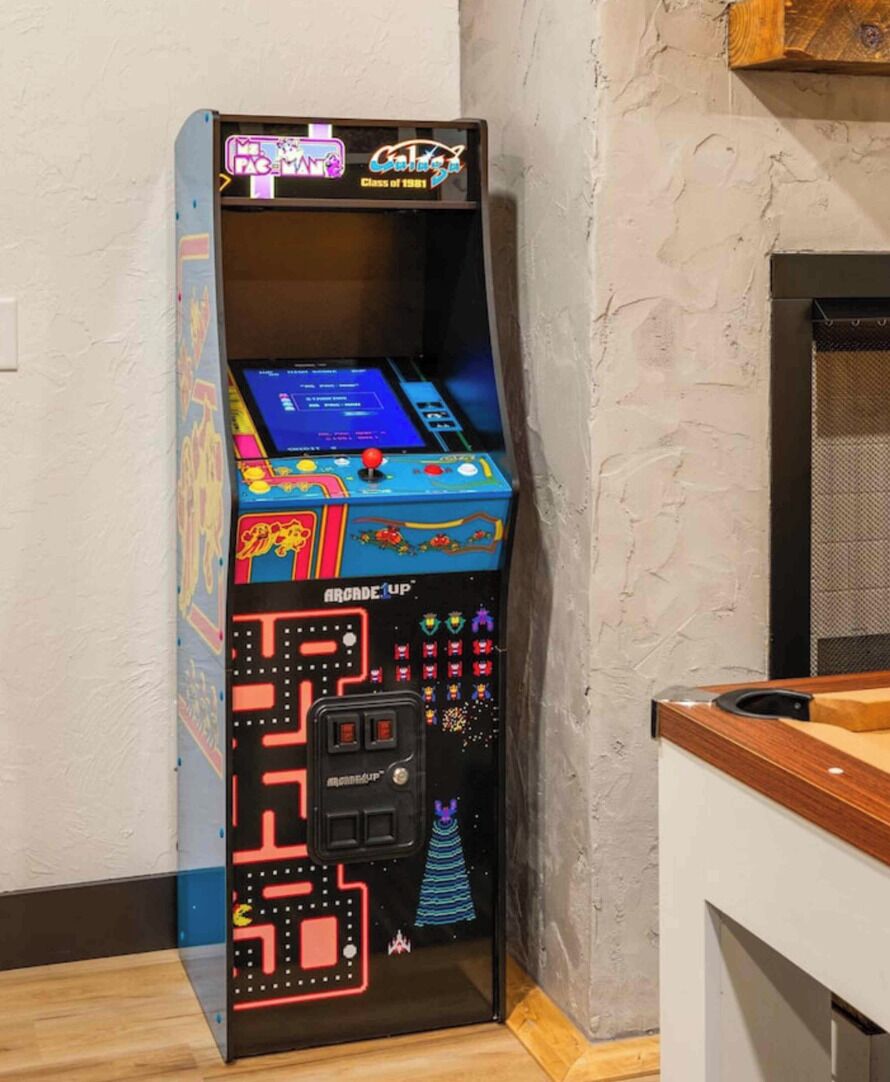 Ein Retro-Spielautomat mit Neonreklame, vor einer strukturierten Wand platziert.