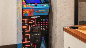 Ein Retro-Spielautomat mit Neonreklame, vor einer strukturierten Wand platziert.
