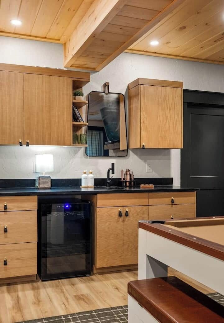 A compact kitchen with wooden cabinets, a black refrigerator, and a built-in oven.