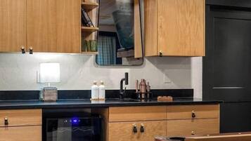 A compact kitchen with wooden cabinets, a black refrigerator, and a built-in oven.
