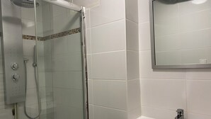 A bathroom with a glass-enclosed shower, a sink, and a mirror. - Apartment in Downtown Chalamont (Chalamont)