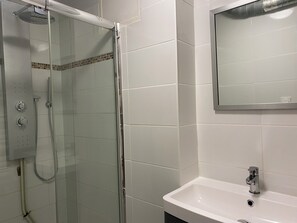 Ein Badezimmer mit Duschkabine, Waschbecken und Spiegel.