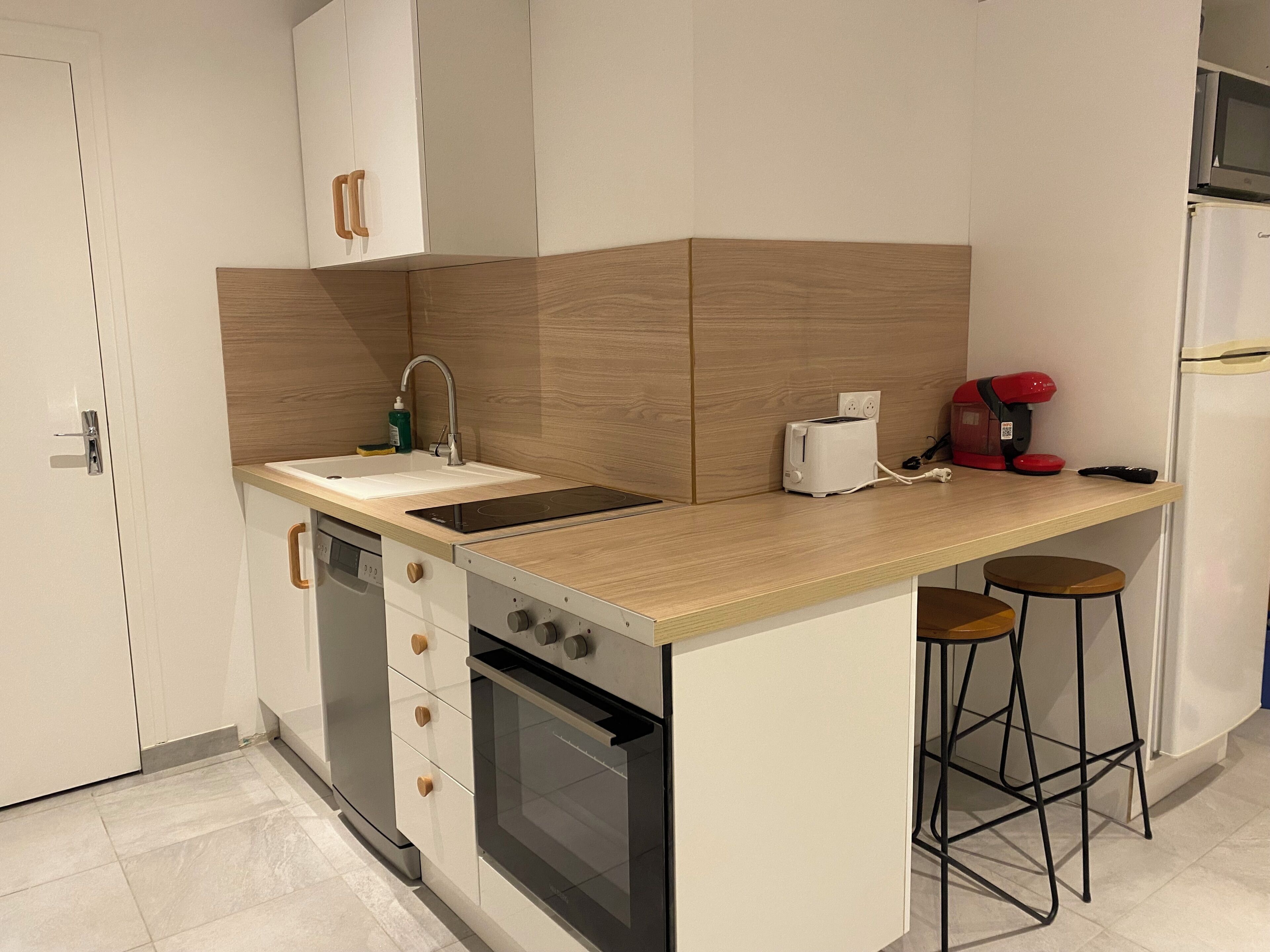 Cocina compacta con lavabo, tostadora, cafetera y refrigerador.