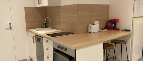 Eine kleine Küche mit Spüle, Toaster, Kaffeemaschine und Kühlschrank.