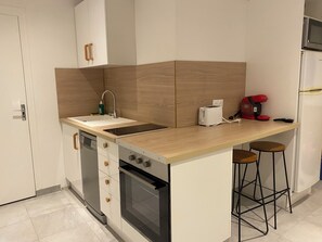 Eine kleine Küche mit Spüle, Toaster, Kaffeemaschine und Kühlschrank.