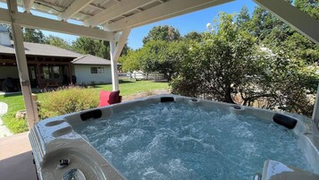 Un jacuzzi con cubierta de madera y un patio techado.