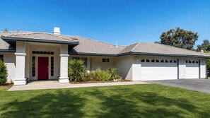 Ein Wohnhaus mit roter Tür, Garage und gepflegtem Rasen.