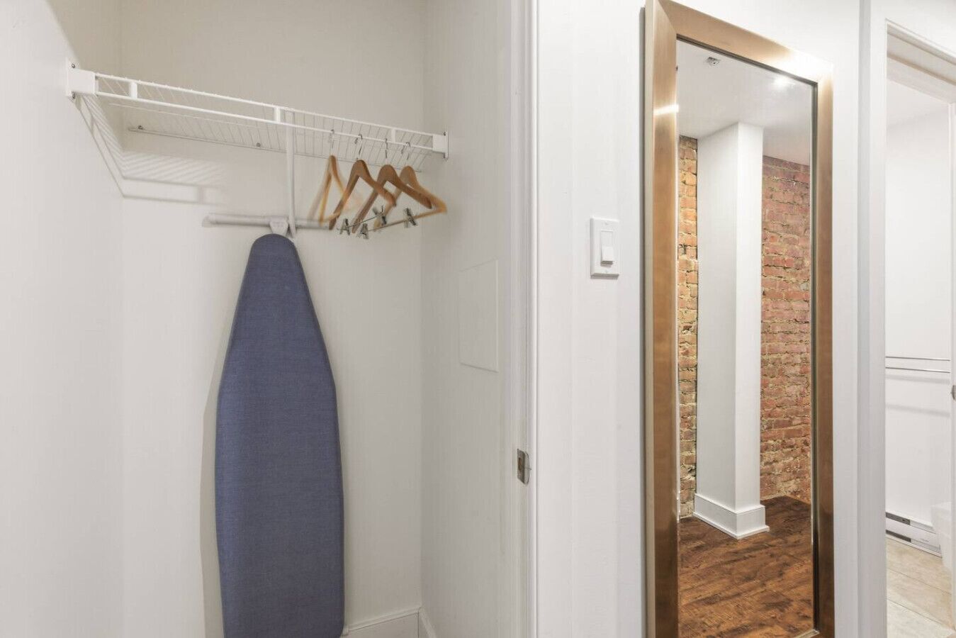 Ein Zimmer mit weißer Wand, einem Kleiderständer und einem an der Wand liegenden Surfbrett.
