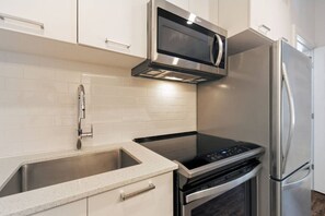 Eine Küche mit Edelstahlgeräten, darunter Mikrowelle, Backofen und Kühlschrank.