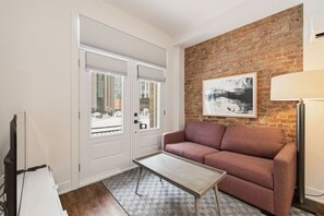 A room with a brick wall, a sofa, a coffee table, and a lamp. - Cozy Montreal 1BR • Steps to Old Port (Montreal)