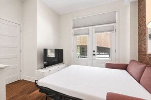 Ein Schlafzimmer mit einem Bett, einem Fernseher, einem Kleiderschrank und einer Backsteinwand.