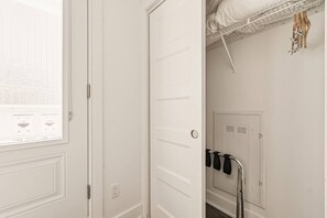 A white door with a window, a coat rack with hangers, and a white wall with a vent. - Modern 1BR • Walk to Old Port (Montreal)