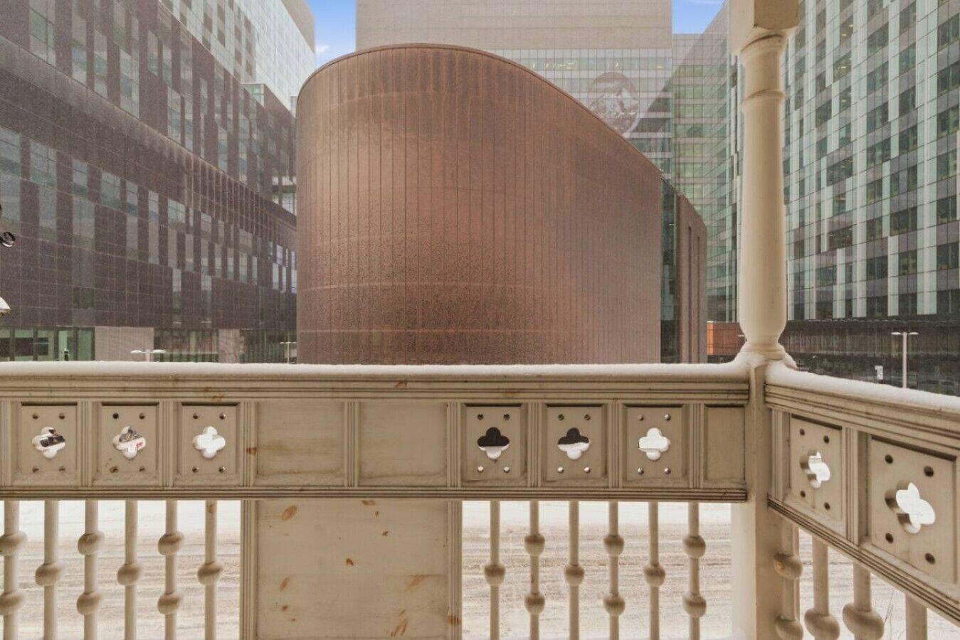Un bâtiment moderne à la façade incurvée, agrémenté d’une clôture en métal décorative aux motifs ajourés, et un ciel dégagé.
