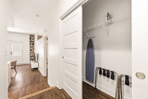 A hallway with a white door, a stone wall, a white cabinet, and a chair. - Modern Downtown Montreal 2-Bedroom • Steps to Old Port (Montreal)