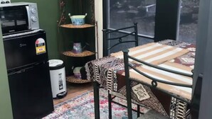 Ein kleiner, abgeschlossener Patio-Bereich mit Tisch, Stühlen, einer Mikrowelle, einem Mülleimer und einem Blumentopf.