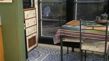 A room with a dining table, chairs, a patterned rug, a microwave, and a cabinet.