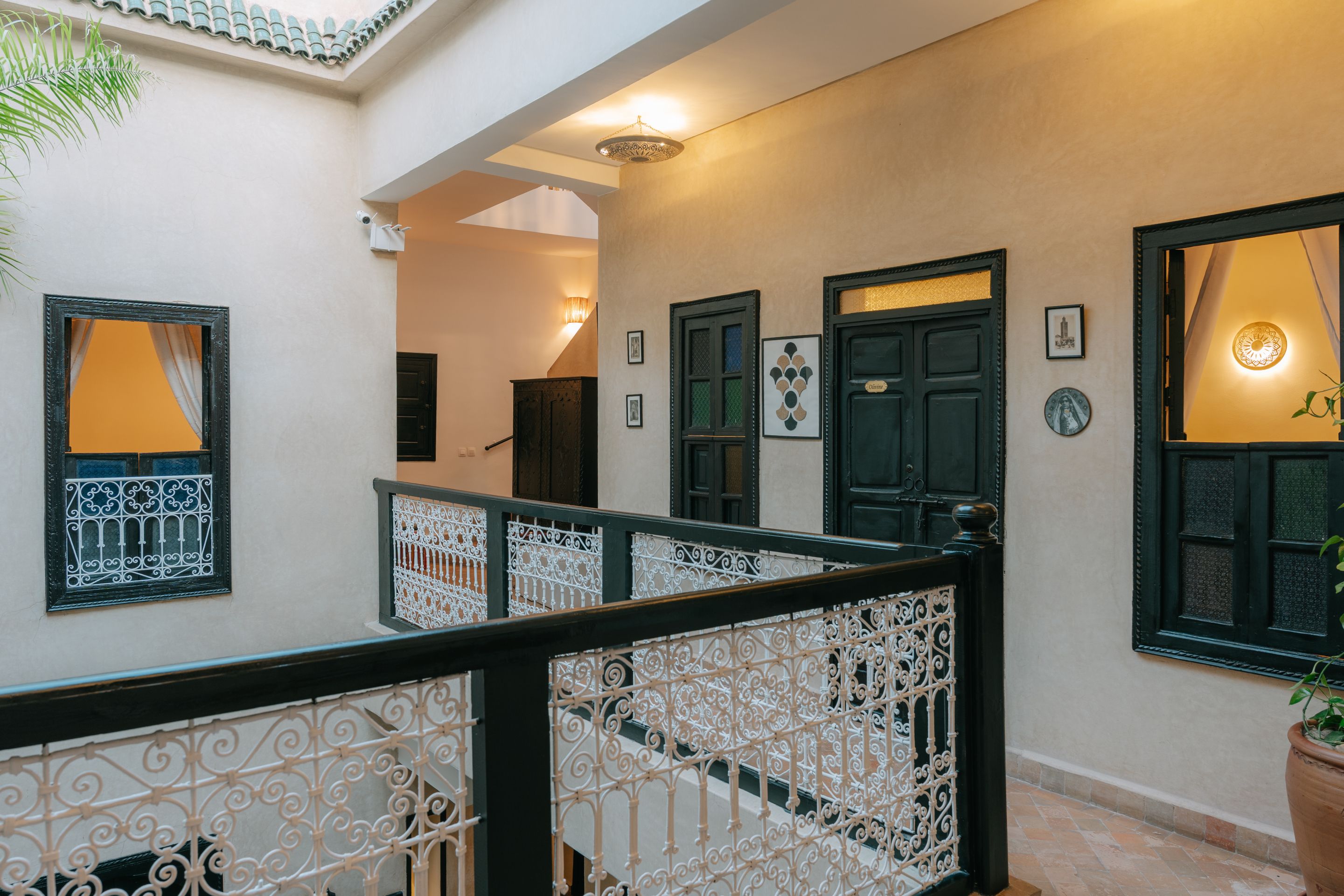 Una escalera con barandillas blancas ornamentales, una pared con obras de arte enmarcadas y una puerta con un panel de vidrio decorativo.