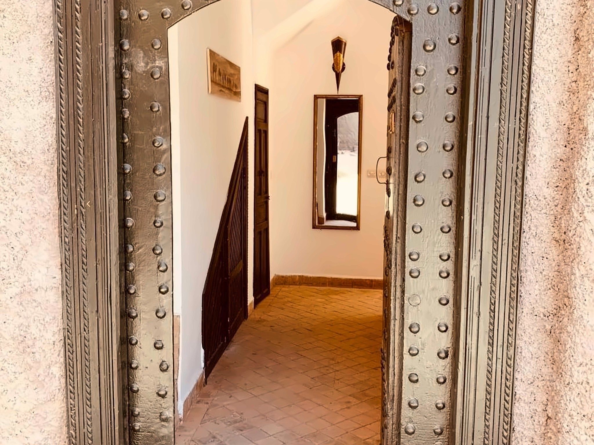 Un pasillo con una puerta de metal y una ventana, que conduce a una habitación con piso de baldosas.