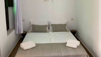 A single bed with a patterned bedspread, two pillows, and two folded towels.