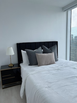 Un dormitorio moderno con una cama grande, una mesita de noche y una lámpara.