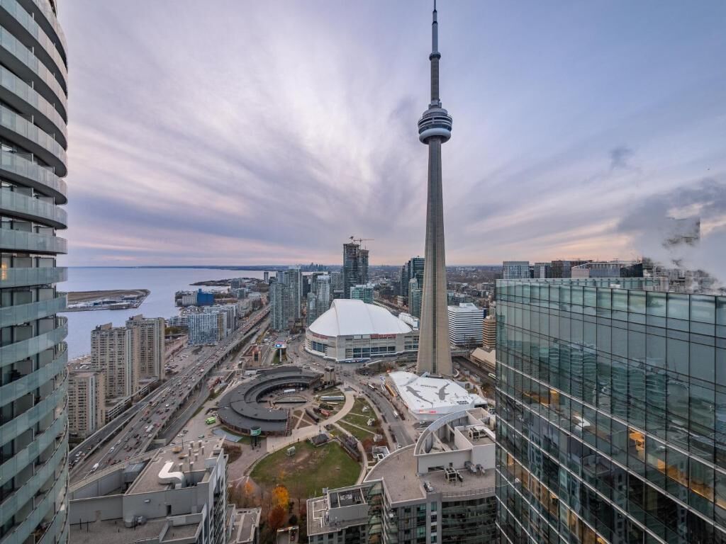 A high-rise building with a distinctive tower, surrounded by modern architecture and a waterfront.