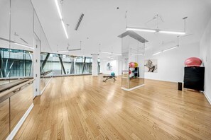 A spacious room with wooden flooring, large windows, and exercise equipment. - Luxury Oasis Suites (Toronto)