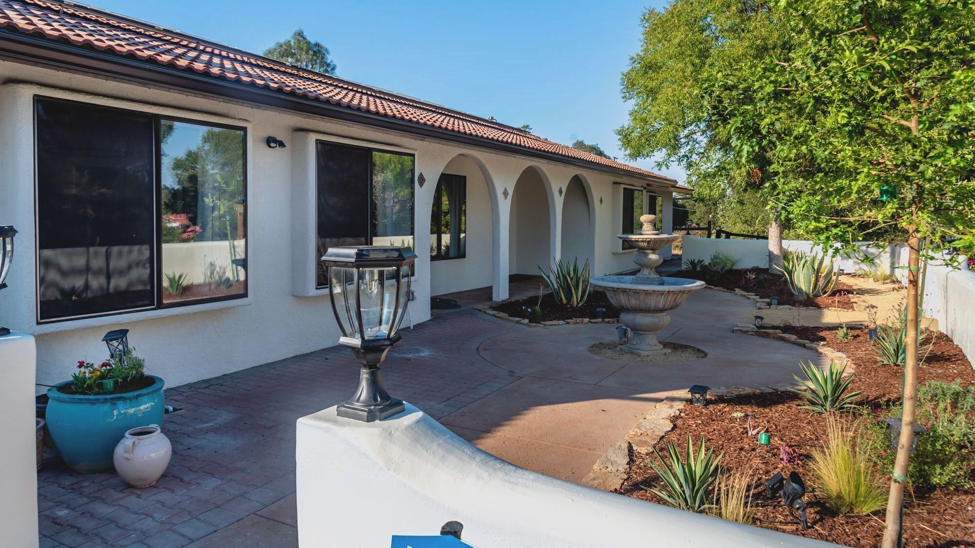 A residential property with a patio, a fountain, and a garden.
