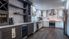 A modern kitchen with a built-in oven, stainless steel appliances, and a patterned backsplash.