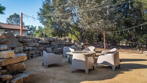 An outdoor patio with stone walls, a table, and four chairs. - Na Hoku Ranch by Avantstay Spanish Hacienda + Spa + Court 5.5 Acres Near Paso (Atascadero)