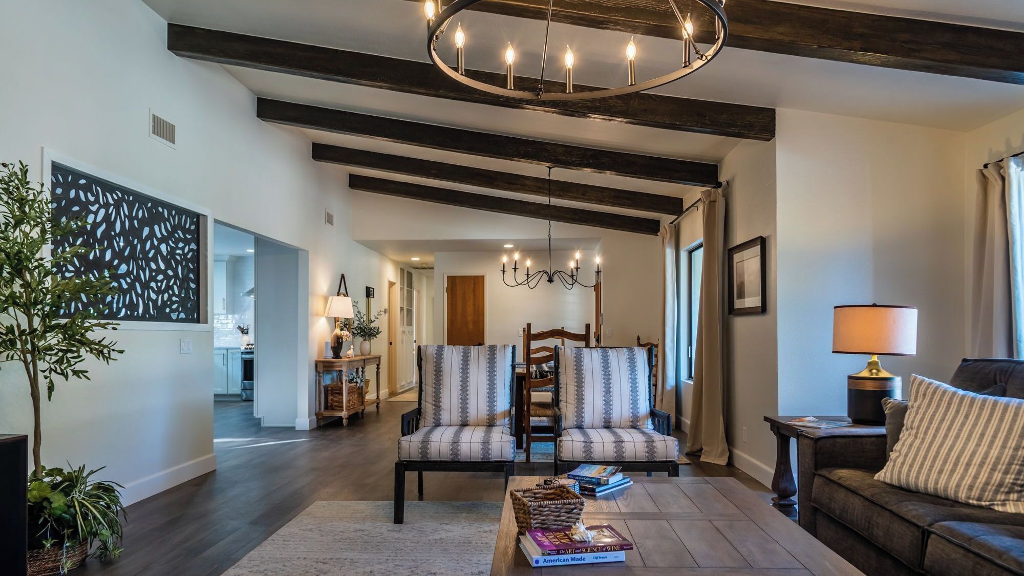 A modern living room with a fireplace, a chandelier, and a dining area with striped chairs.
