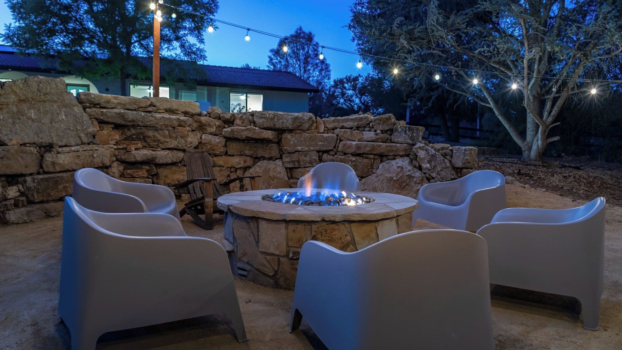 An outdoor seating area with a stone fire pit and chairs.