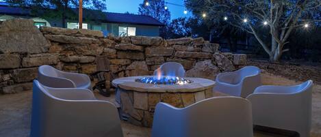 An outdoor seating area with a stone fire pit and chairs.