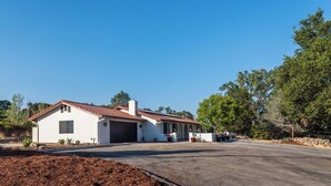 A single-story house with a red-tiled roof, a garage, and a small porch with potted plants. - Na Hoku Ranch by Avantstay Spanish Hacienda + Spa + Court 5.5 Acres Near Paso (Atascadero)