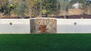 A wall with a decorative tile pattern, a potted plant, and a small rock feature.