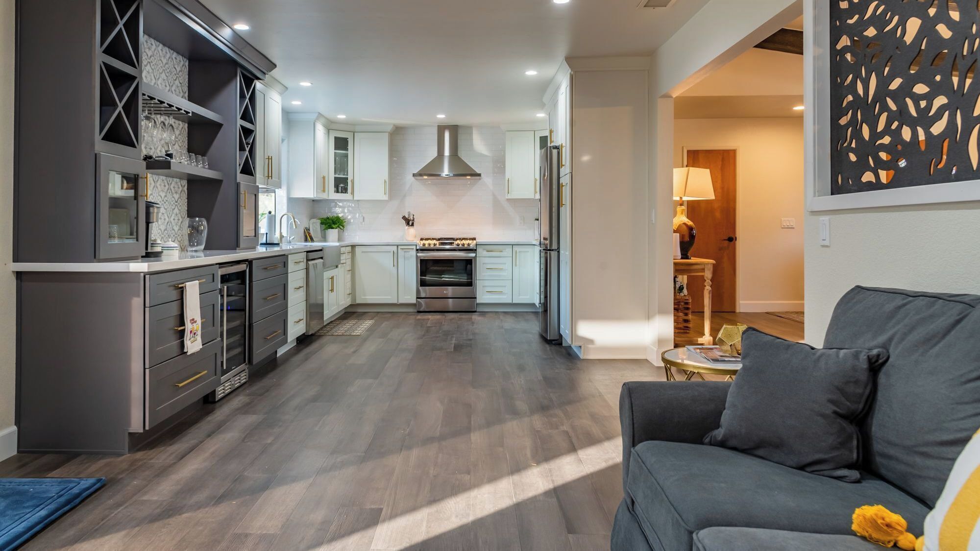 A modern kitchen with a central island, built-in appliances, and a dining area with a sofa.