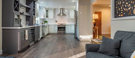 A modern kitchen with a central island, built-in appliances, and a dining area with a sofa.