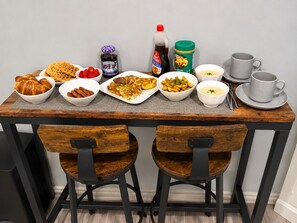A dining table with various food items and condiments, accompanied by two chairs and a set of white cups and saucers. - Maple Haven | Spacious 3BR Private Luxury Suite • Huge Yard • Sleeps 6 (Pickering)