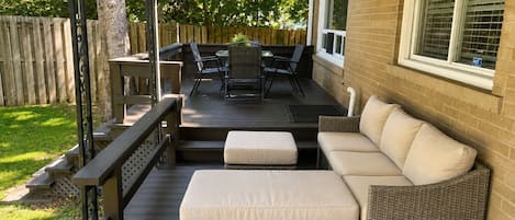 A covered patio with a wicker sofa, a table, and chairs.