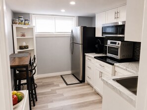 A compact kitchen with white cabinets, a black refrigerator, a microwave, and a sink.