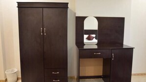 A dark wooden wardrobe with two doors and a mirror above a dresser. - Manarat Al Mashaer Hotel (Makkah)